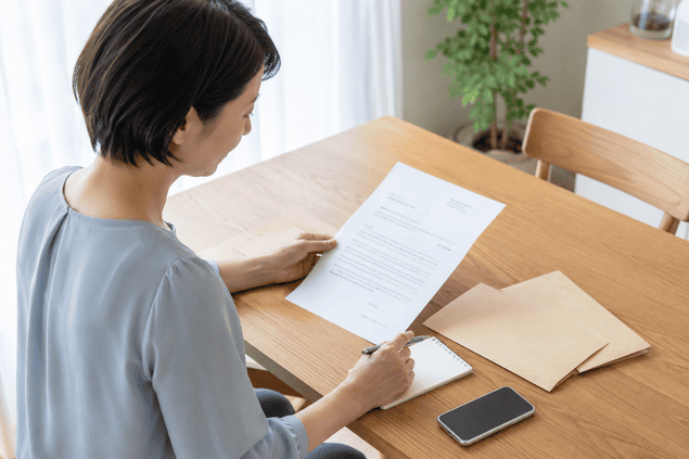 返済請求のための書面と封筒を確認する女性