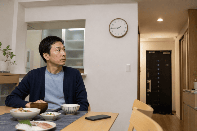 妻の帰宅を待ちながら玄関と時計を気にする夫