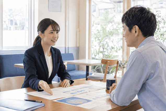 カフェで男性顧客に保険の説明をする生保レディ
